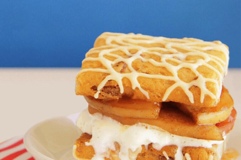 Fiber One Cinnamon Apple & Vanilla Ice Cream Sandwich Recipe oozing vanilla ice cream on a plate with a blue and white background.