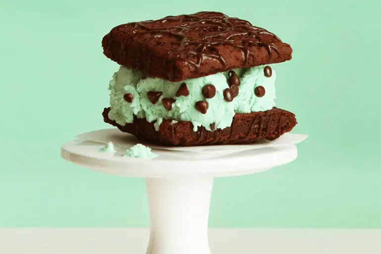 Fiber One Mint Chocolate Chip Ice Cream Sandwich Recipe on a white cake pedestal with a mint green background
